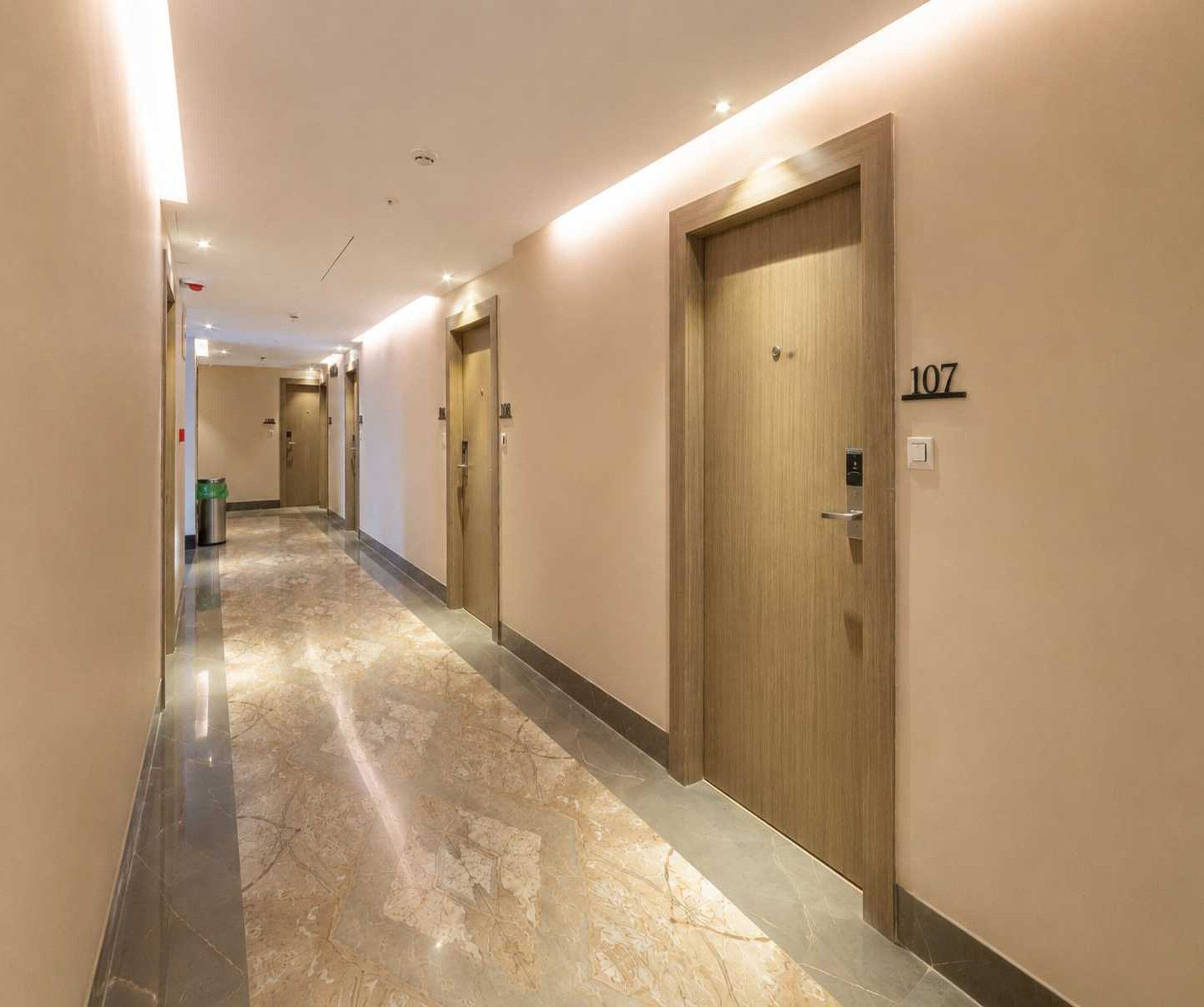 A hotel hallway with doors numbered 107 and 108, a trash bin, and a lighted ceiling.