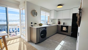 Una cucina moderna con lavatrice, lavello e una finestra vista città.