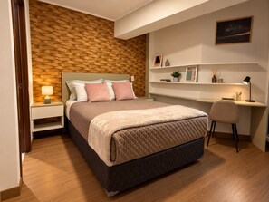 Un dormitorio con una cama, mesitas de noche, un escritorio y una silla.
