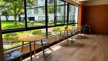 Un interior moderno con ventanas amplias, suelo de madera y una zona de estar con mesas y sillas.
