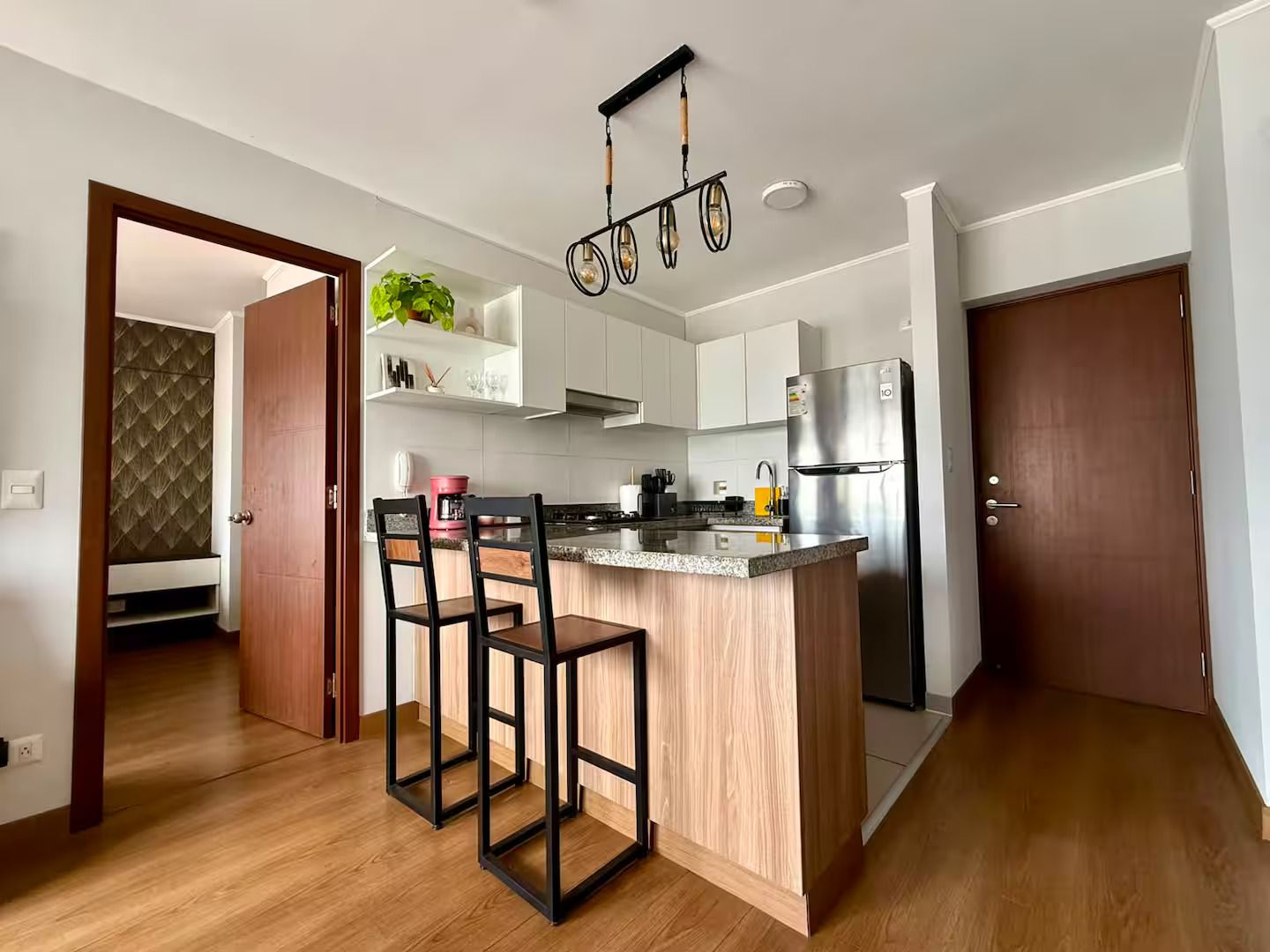 A modern kitchen with a central island, stainless steel appliances, and a hanging light fixture.