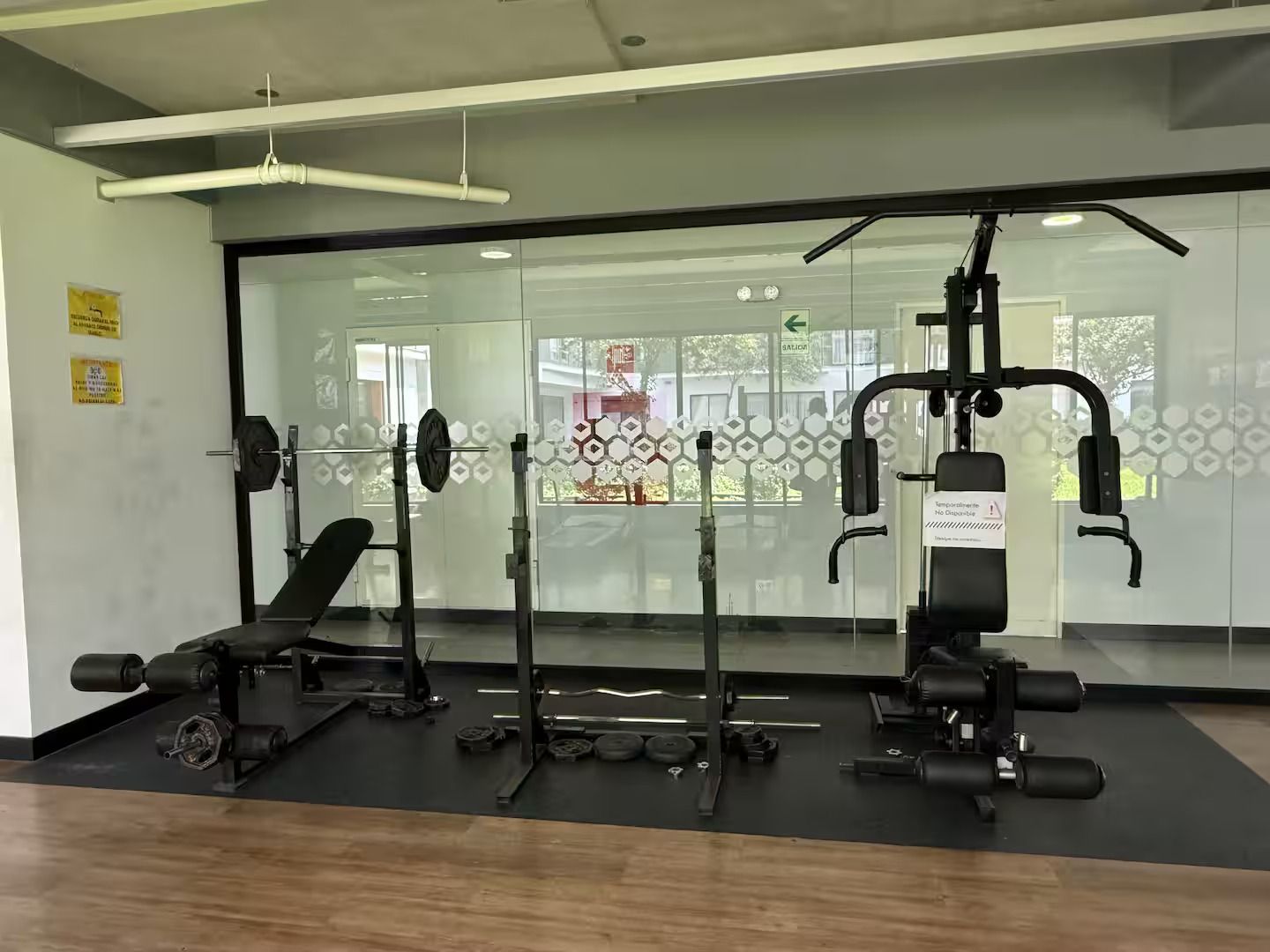 Un gimnasio con equipo de levantamiento de pesas, una banca y un espejo grande.