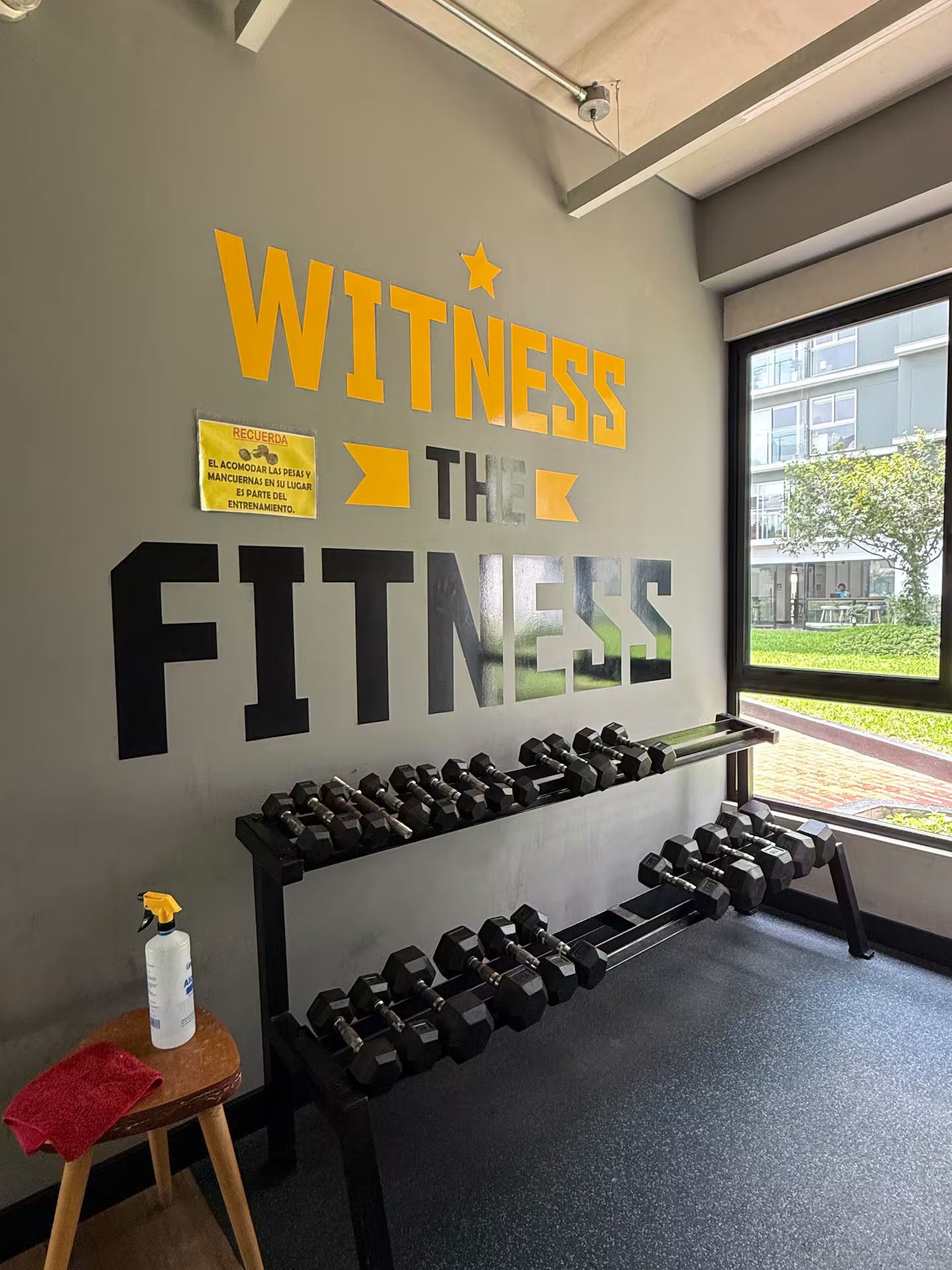 A gym with a motivational sign on the wall and a rack of dumbbells.