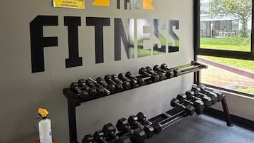 A gym with a motivational sign on the wall and a rack of dumbbells.