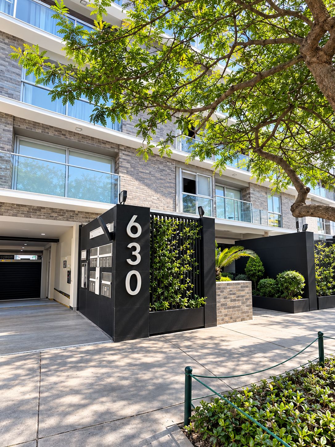 A modern building with a large number sign, a gated entrance, and a well-maintained garden area.