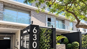 Un edificio moderno con un portón de acceso negro identificado con el número '630' y un camino de entrada pavimentado.
