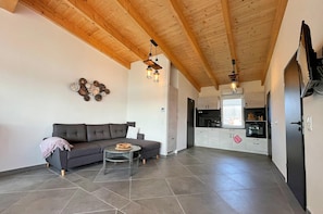 A living room with a sofa, a small round table, and a kitchen in the background. - Bungalow mit Seeblick in Klein Labenz (Warin)