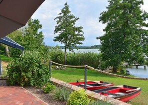 A lakeside view with a boat docked on the shore, surrounded by greenery and a clear sky. - Bungalow mit Seeblick in Klein Labenz (Warin)