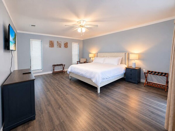 A bedroom with a bed, bedside tables, a TV, and a ceiling fan.