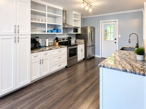 Una cocina moderna con armarios blancos, electrodomésticos de acero inoxidable y encimera de mármol.