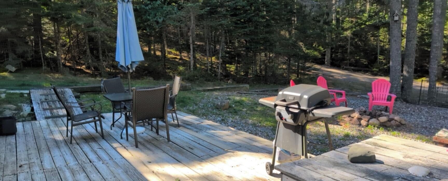 Une terrasse extérieure équipée d’un barbecue, de chaises et d’une table.