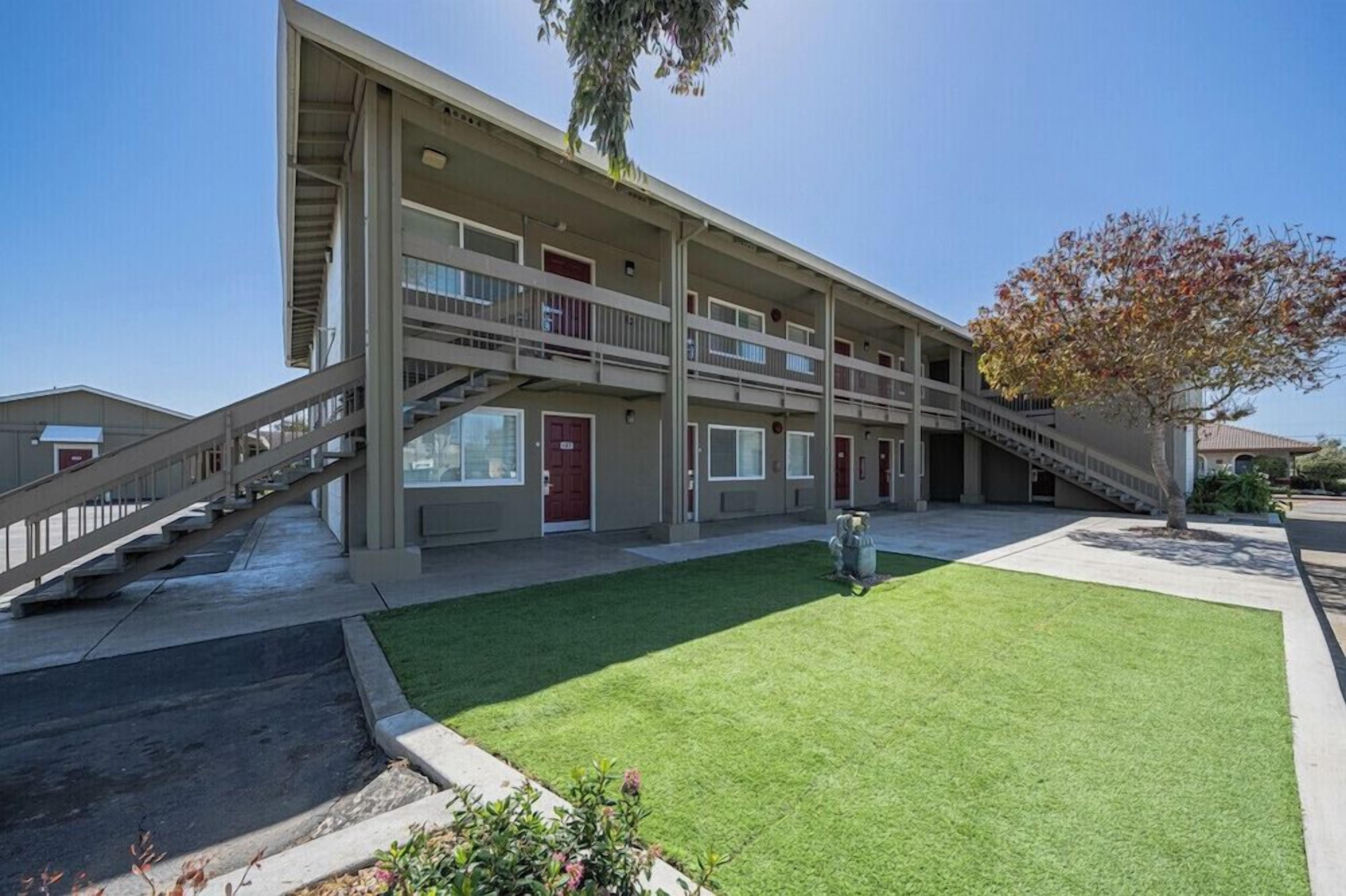 A multi-story building with a central staircase, a flat roof, and a small lawn area.