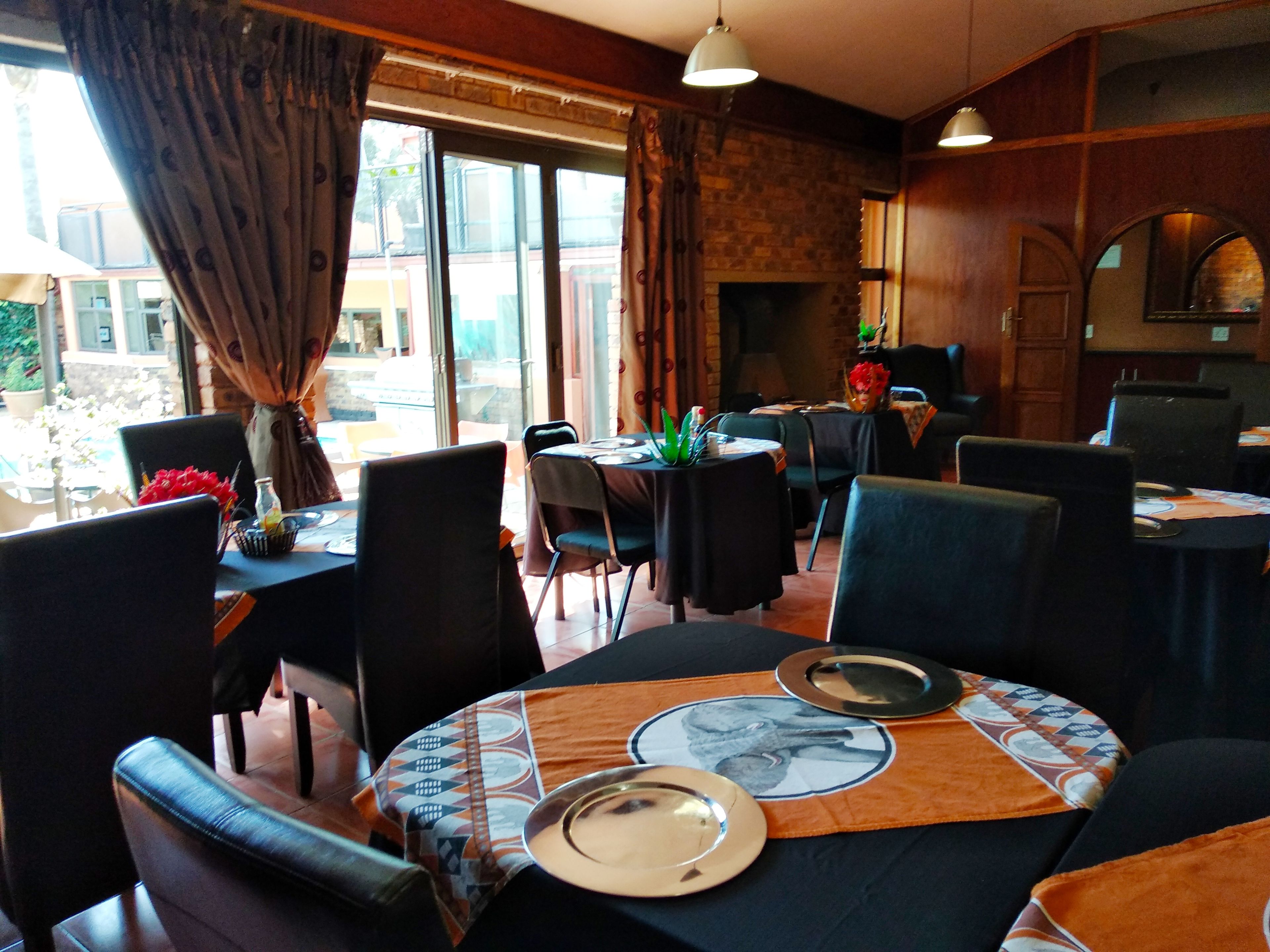 A restaurant with tables set for dining, chairs, and a fireplace.