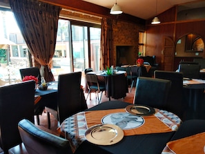 Un restaurant avec des tables dressées, des chaises et une cheminée.
