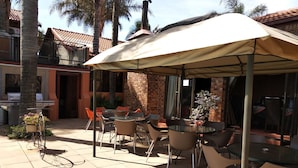 En udendørs patio med pool, overdækket siddeområde og grill.