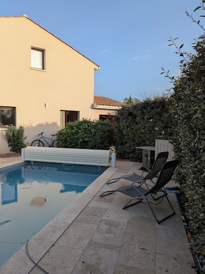 A swimming pool with lounge chairs, a bicycle, and a building with a tiled roof. - House with a pool and hot tub just a stone's throw from the Canal du Midi. (Saint-Nazaire-d'Aude)