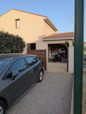 A residential garage with a car parked outside, a washing machine inside, and a metal gate. - House with a pool and hot tub just a stone's throw from the Canal du Midi. (Saint-Nazaire-d'Aude)