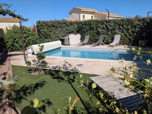 Ein Schwimmbad mit Liegestühlen, eine kleine Gartenhütte und ein gepflegter Rasen.