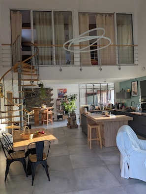 A spacious loft with a high ceiling, a mezzanine level, a kitchen with a central island, and a dining area with a wooden table and chairs. - House with a pool and hot tub just a stone's throw from the Canal du Midi. (Saint-Nazaire-d'Aude)