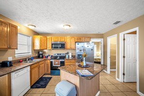 A kitchen with wooden cabinets, stainless steel appliances, and a granite countertop. - The Retro Cove: Minutes to beach, 2 Pools (Panama City Beach)