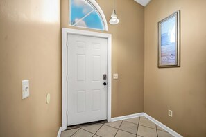 A hallway with a white door, a light fixture, and a framed picture on the wall. - The Retro Cove: Minutes to beach, 2 Pools (Panama City Beach)