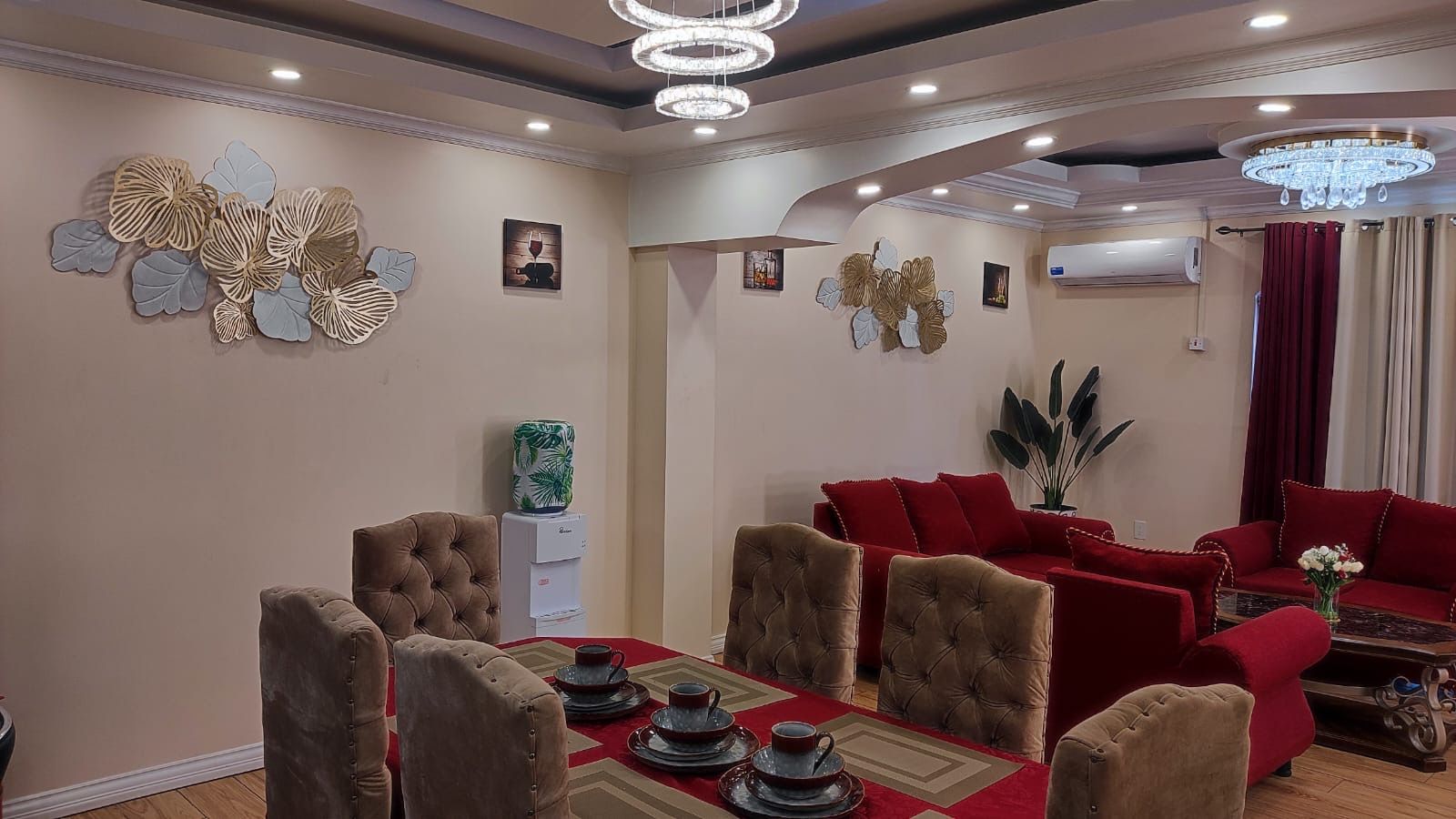 A dining area with a red tablecloth, a red sofa, and a chandelier.