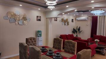 A dining area with a red tablecloth, a red sofa, and a chandelier.