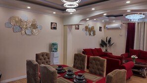 Un coin repas avec une nappe rouge, un canapé rouge et un lustre.