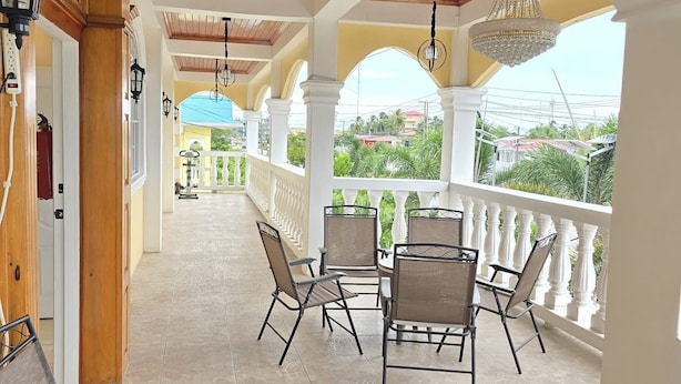 A covered outdoor area with a tiled floor, white columns, and a railing overlooking a residential area. - Atlantic Suites Luxury Apartments (Anna Regina)