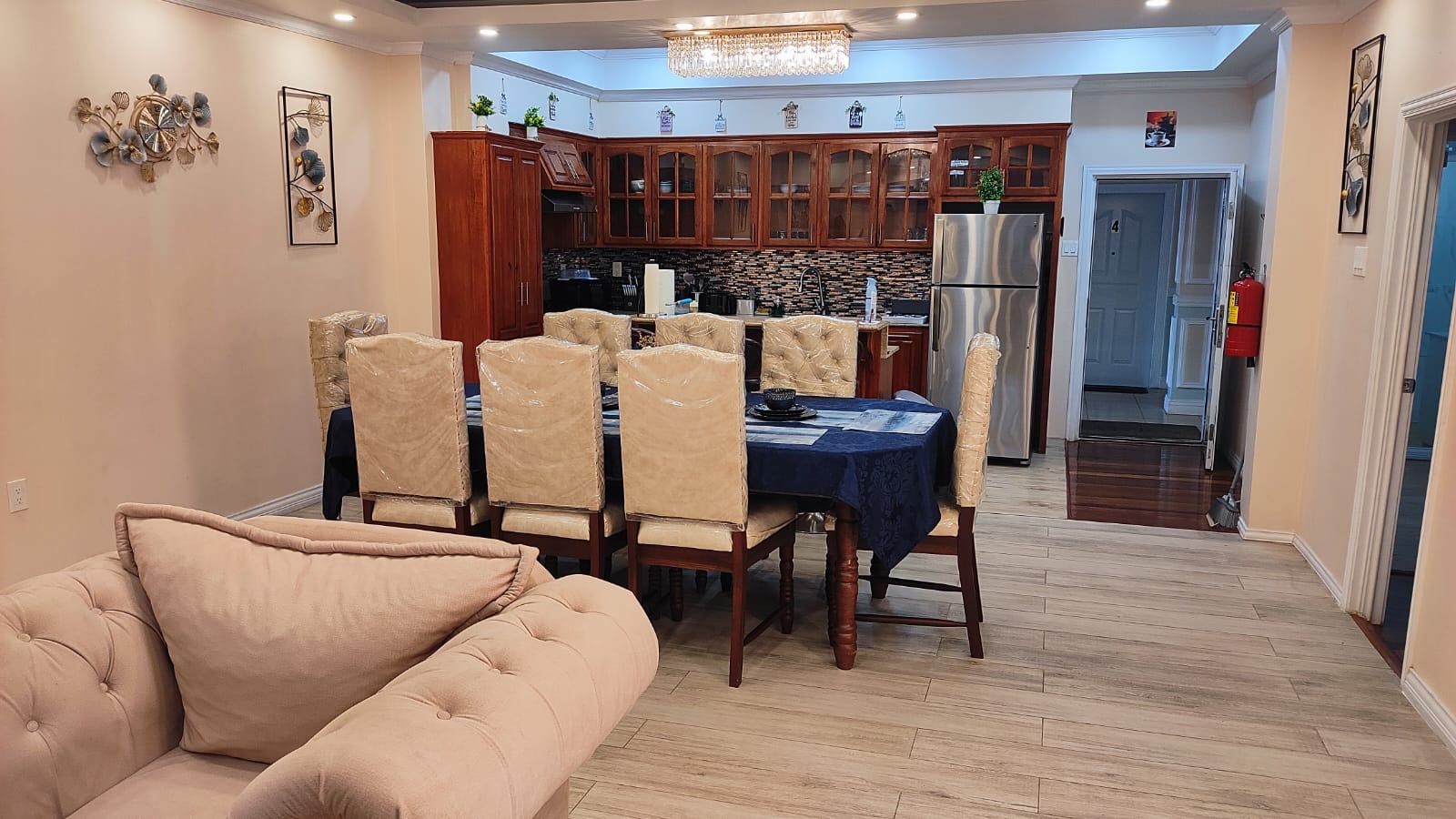 Un comedor con mesa y sillas, una cocina al fondo y un extintor cerca de la puerta.