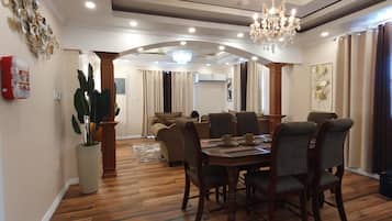 Un comedor con piso de madera, una araña y una mesa preparada para cuatro comensales.