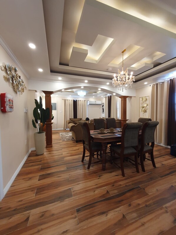 Un comedor con piso de madera, una araña y una mesa preparada para cuatro comensales.