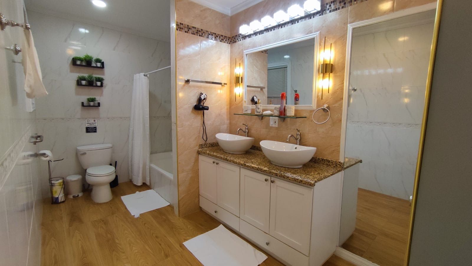 Casa de banho com duas pias, chuveiro e sanita.