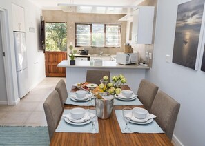 A modern kitchen with a dining area set for a meal. - Brenton Breakers (Knysna)