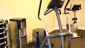 Un gimnasio equipado con una bicicleta estática, un dispensador de agua y una cinta de correr.