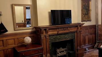 A room with a fireplace, a television, a globe on a dresser, and a large mirror.