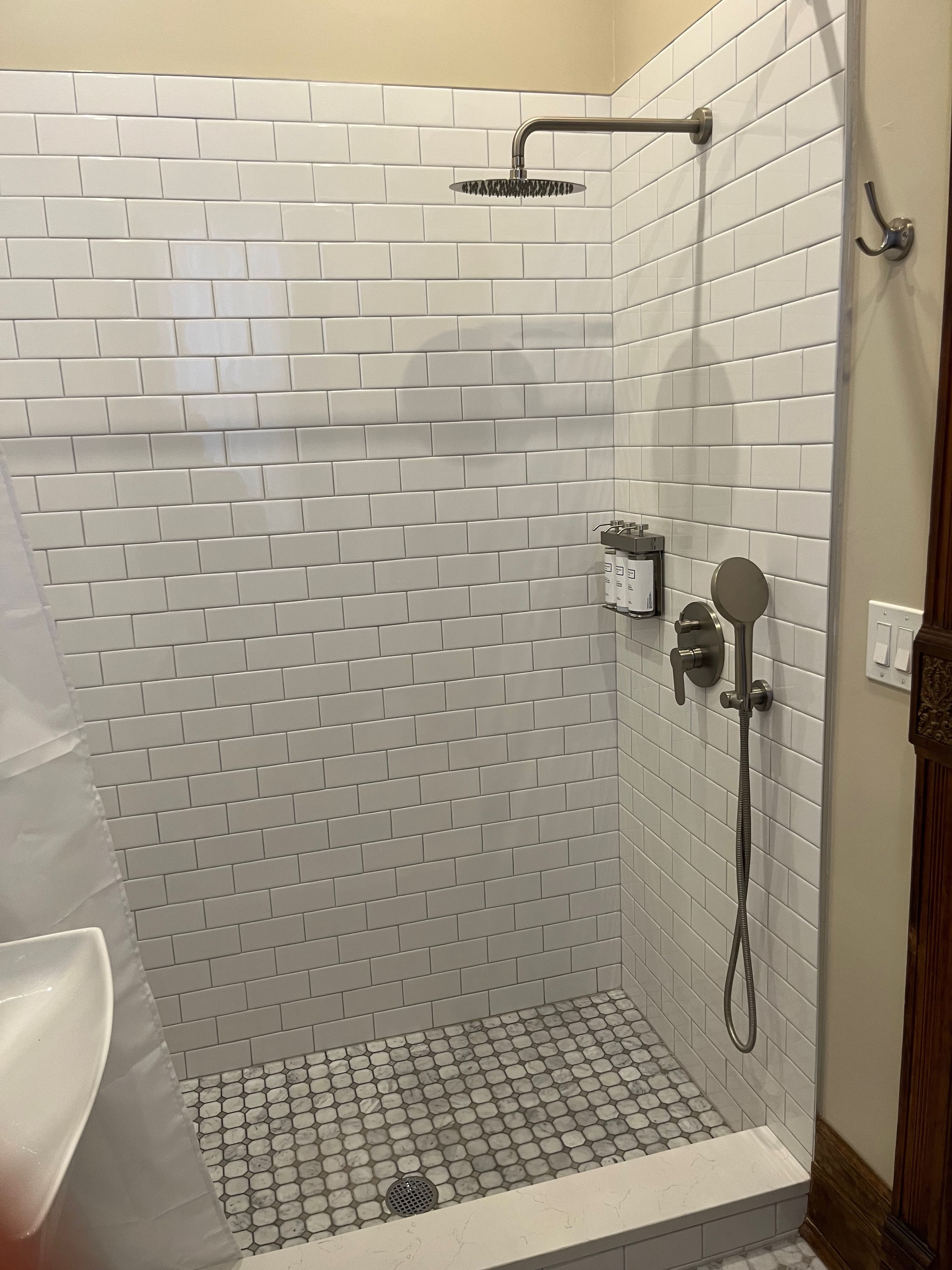 Eine Dusche mit weiß gefliesten Wänden und einer Duschbrause.