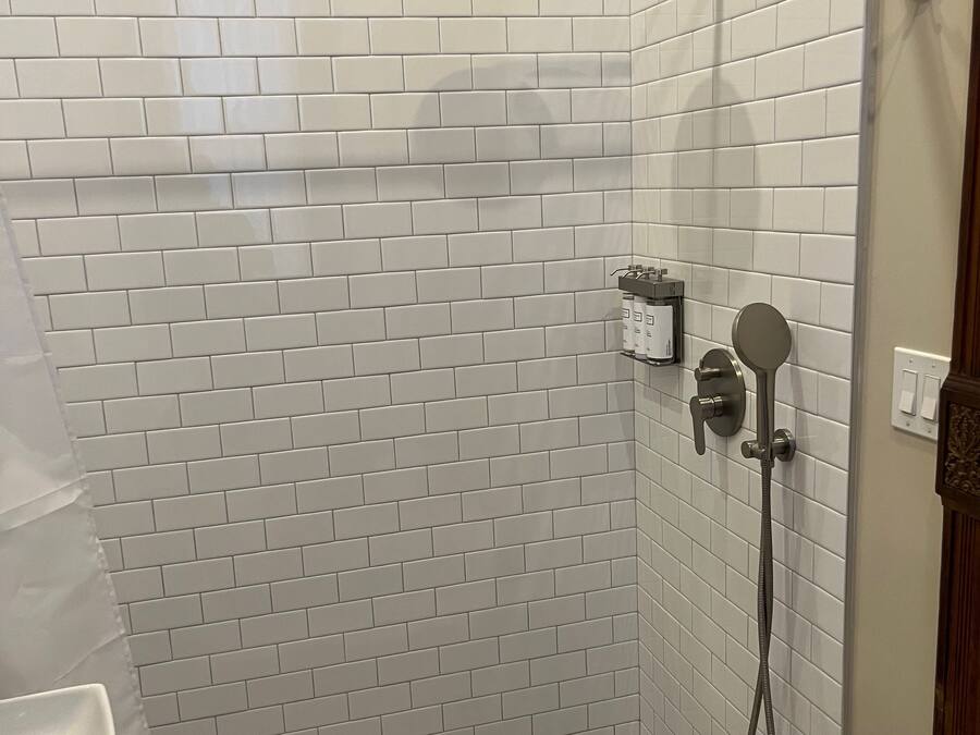 Eine Dusche mit weiß gefliesten Wänden und einer Duschbrause.