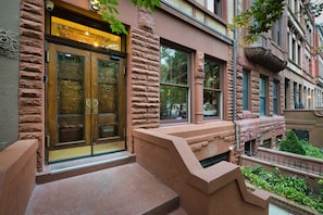 A building facade with a stone exterior, large glass doors, and a small outdoor area with steps.