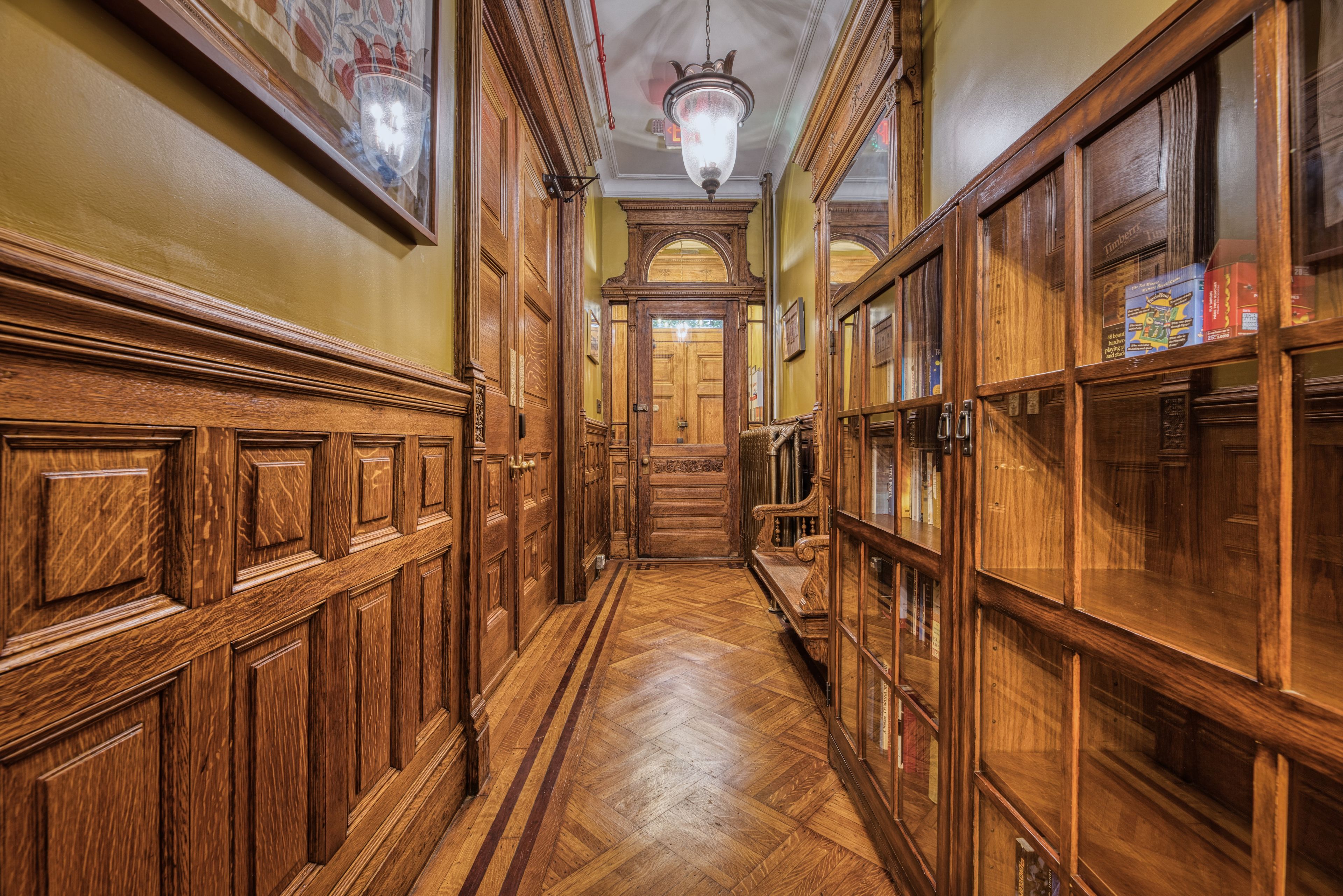 A wooden hallway with ornate doors and a chandelier.