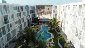 A modern hotel with a central swimming pool, surrounded by lush greenery and palm trees. - Luxury Suite * POOL * BBQ * DOWNTOWN PUNTA CANA (Punta Cana)