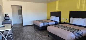 Habitación de hotel con dos camas, un escritorio y una pequeña kitchenette.