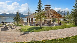 A lodge with a stone chimney, picnic tables, and a view of a lake and mountains. - New 3BR Condo Within Walking Distance to Marina and Mins From Ski Resorts! (Dillon)