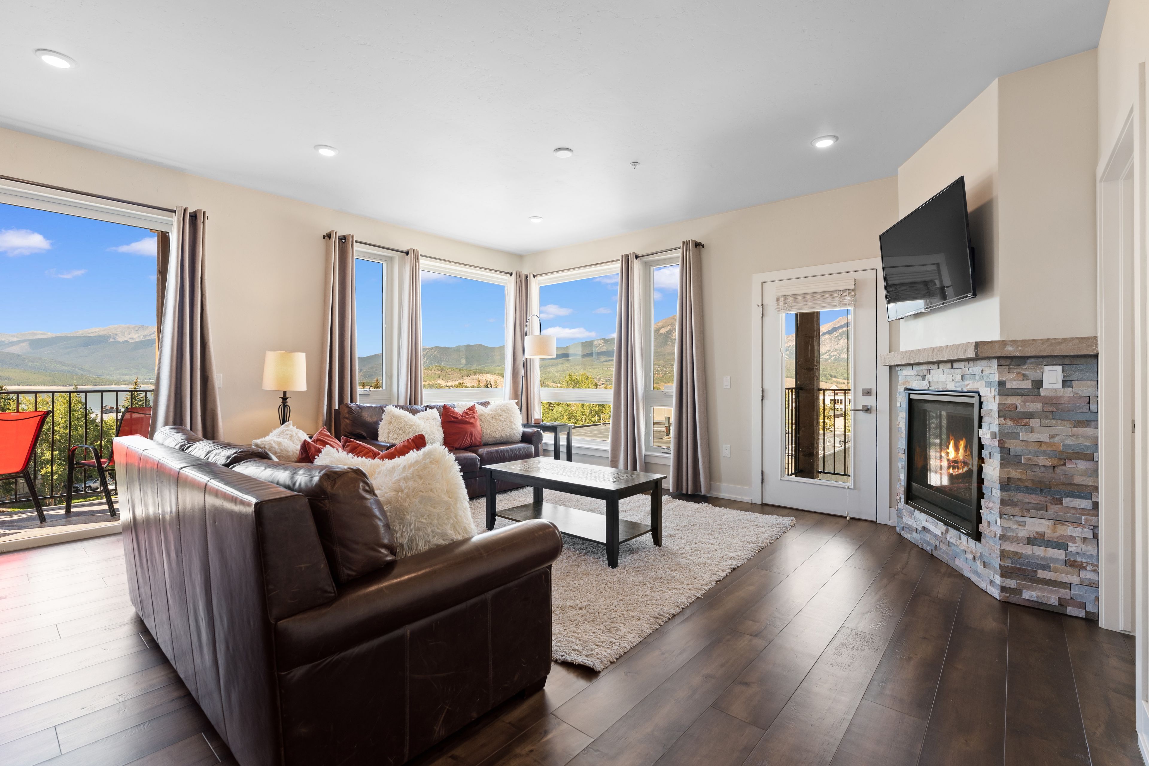 A living room with a fireplace, a sofa, a coffee table, and a view of the mountains.