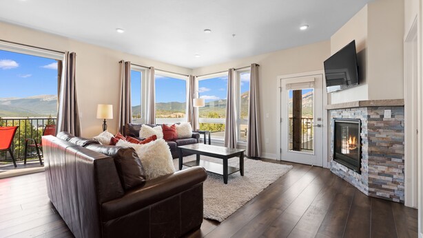 A living room with a fireplace, a sofa, a coffee table, and a view of the mountains. - New 3BR Condo Within Walking Distance to Marina and Mins From Ski Resorts! (Dillon)