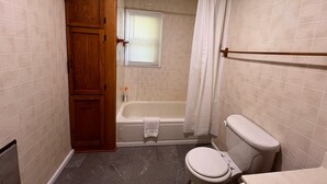Een badkamer met een badkuip, toilet en een houten kastje.
