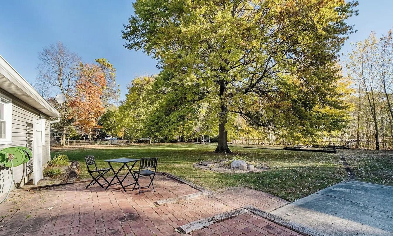 A patio with a brick floor, a table, and two chairs.