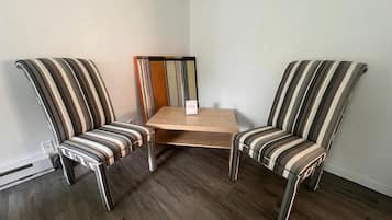 Ein Eckzimmer mit zwei gestreiften Sesseln und einem kleinen Holztisch.