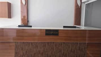 A reception desk with a 'RECEPTION' sign, wooden paneling, and two wall-mounted decorative elements.