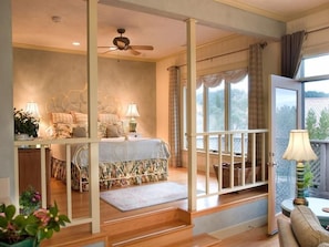Un dormitorio con cama, mesitas de noche, ventana y balcón.